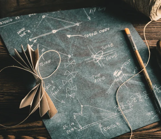 Kite blueprint with paper model and tools on wooden surface — The Better Coffee Blueprint course