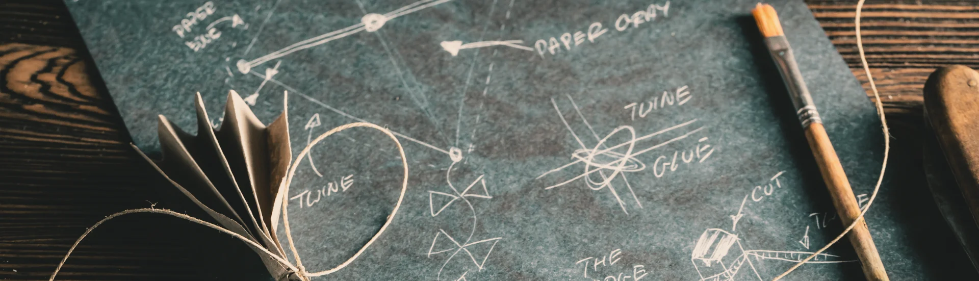 Kite blueprint with paper model and tools on wooden surface — The Better Coffee Blueprint course