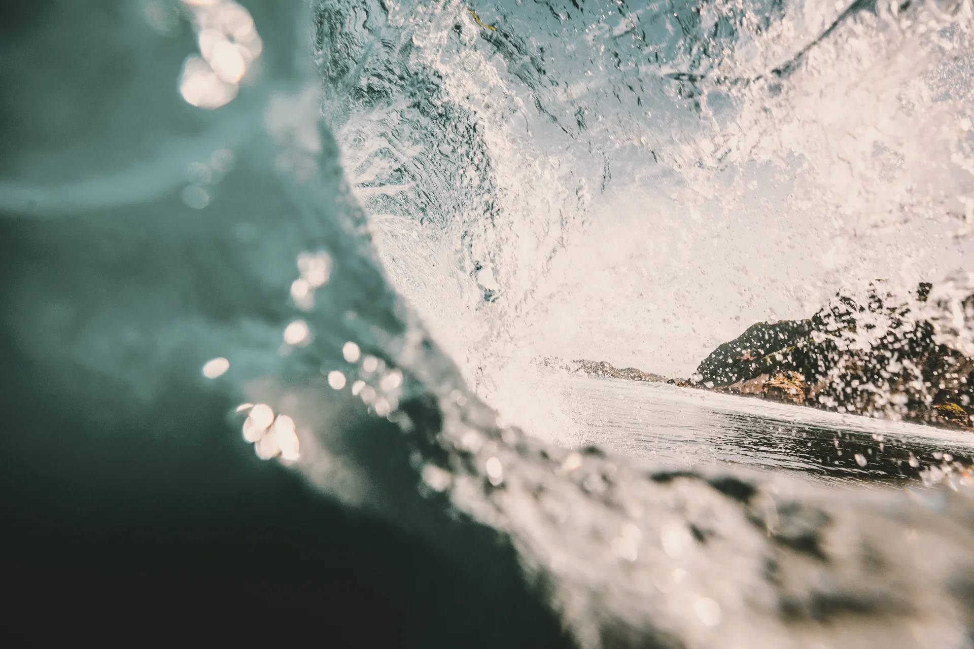 Ocean wave seen from inside with rock in background — Pay-It-Forward solidarity fund hero image